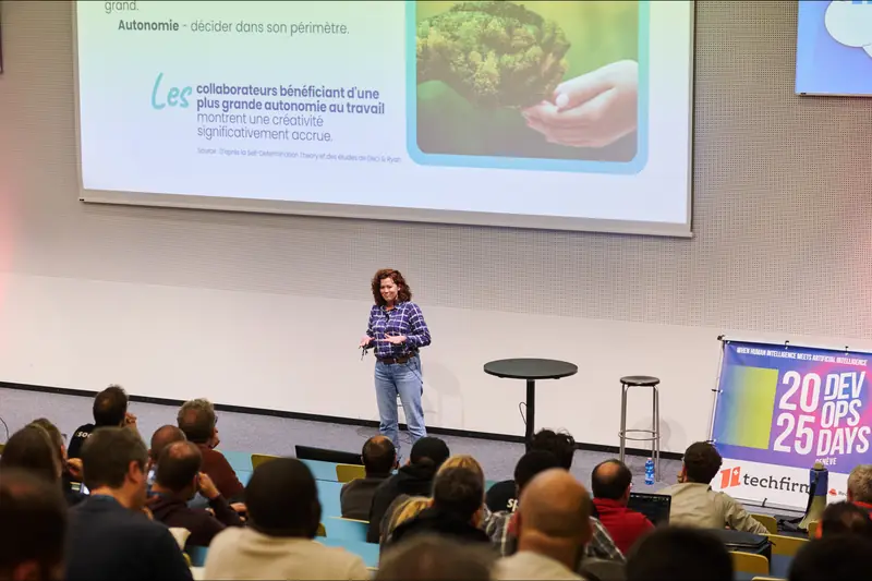 Elsa Baldan sur la scène des DevOpsDays Genève 2025, devant un amphithéâtre de professionnels de la tech