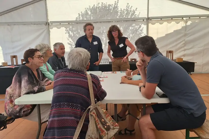 Elsa Baldan et Ghislain Décréau échangent avec des participants attablés sous un chapiteau, au festival Livres en Marches